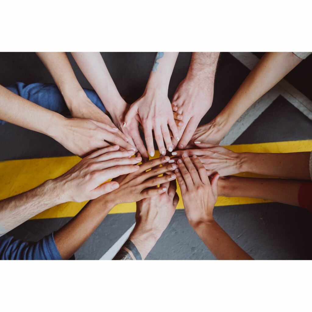 Top view of a team with their hands stretched out to touch each other to explain real time coaching and teamwork.